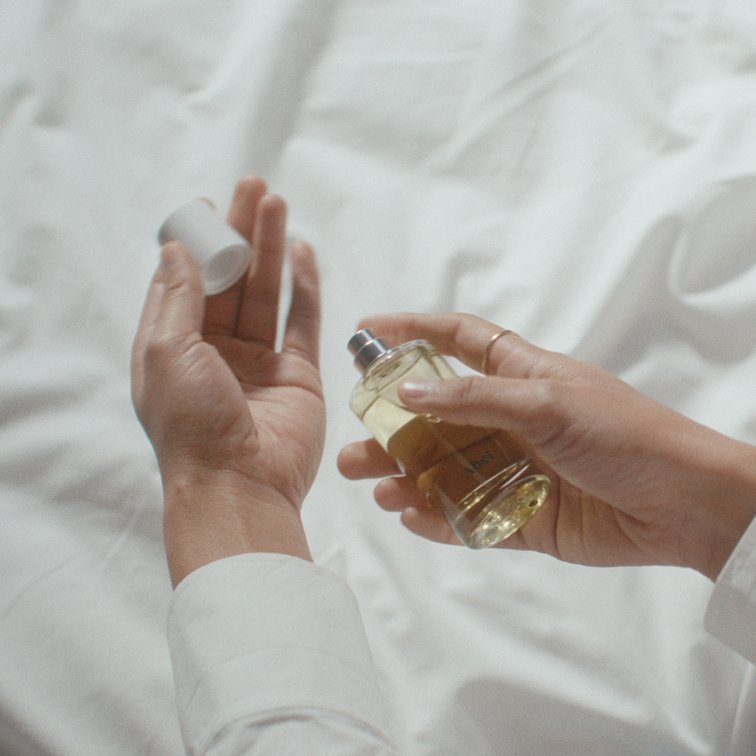 A woman is applying perfume on her wrist