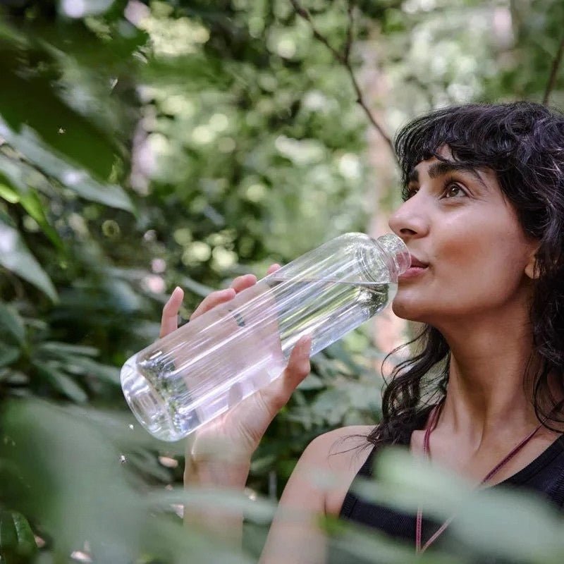 A woman is drinking water in the forest