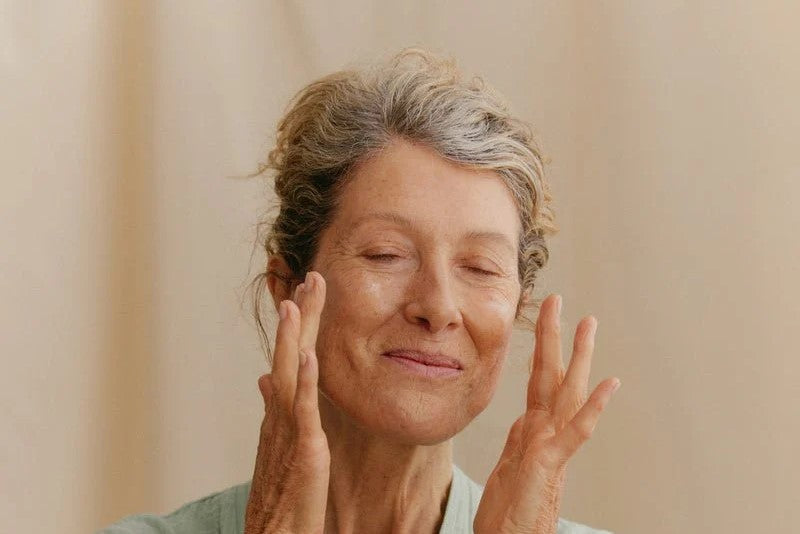 A woman is applying moisturizer on her face